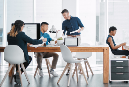 A view from afar of four office workers collaborating in a well-lit office.