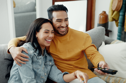Man and woman holding remote while watching TV
