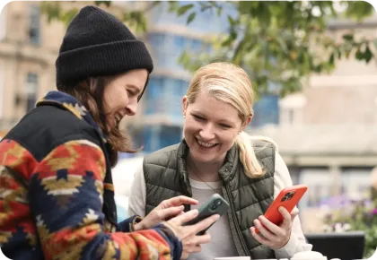 Two women outside holding mobile phones