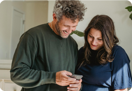 Man and woman smiling while looking at a mobile device