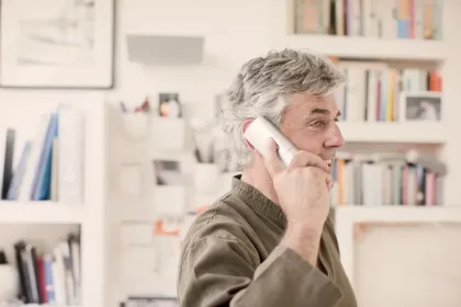Older man holding a home phone up to his ear
