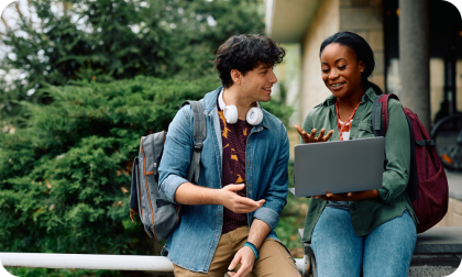 Man and woman standing outside holding laptop
